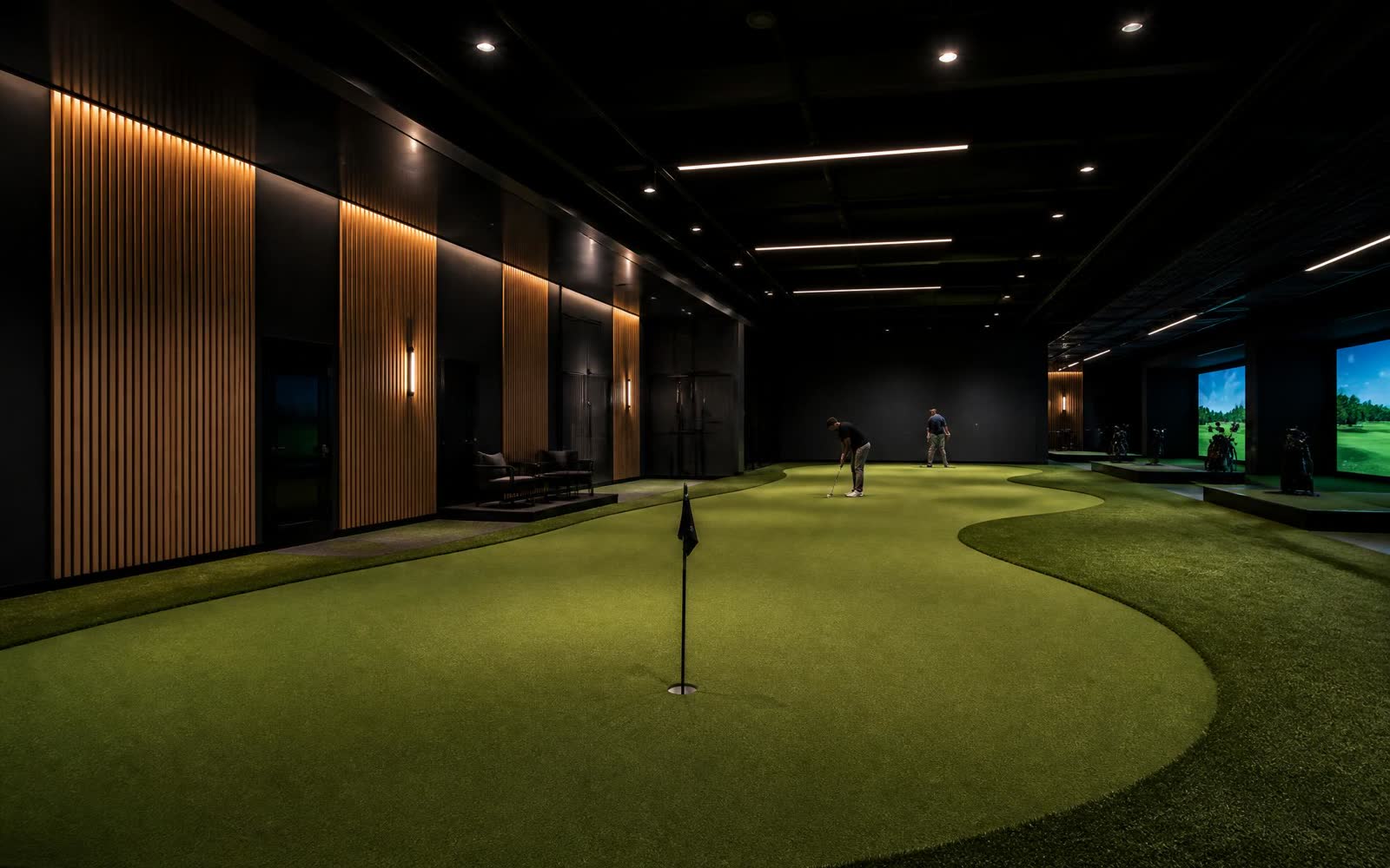 Inomhusanläggning för golfträning med stor puttinggreen och träpaneler