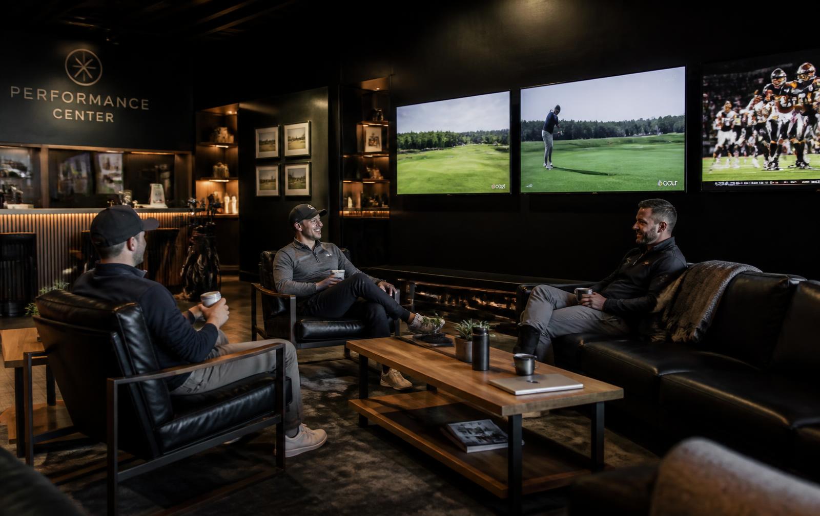 Lounge och café på The Progress med fåtöljer, träbord och TV-skärmar med golf