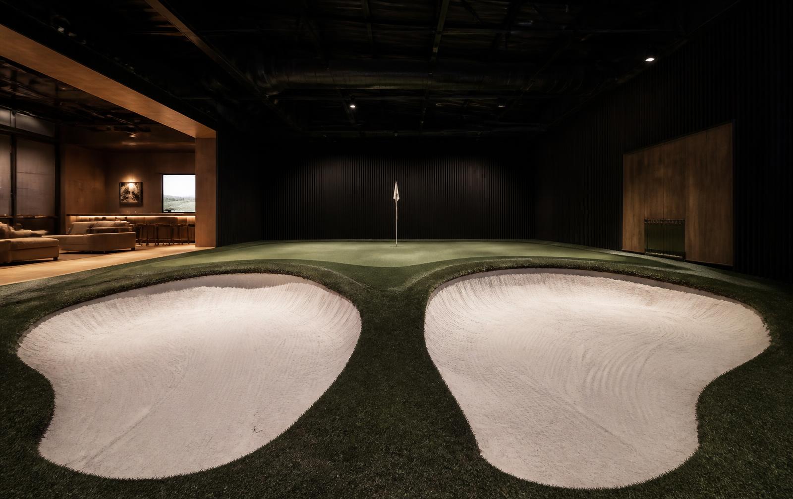 Två inomhusbunkrar med riktig sand bredvid varandra mot en gemensam bunker-green